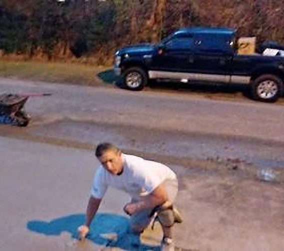 A worker on his knees finishing the edge of a fresh concrete slab